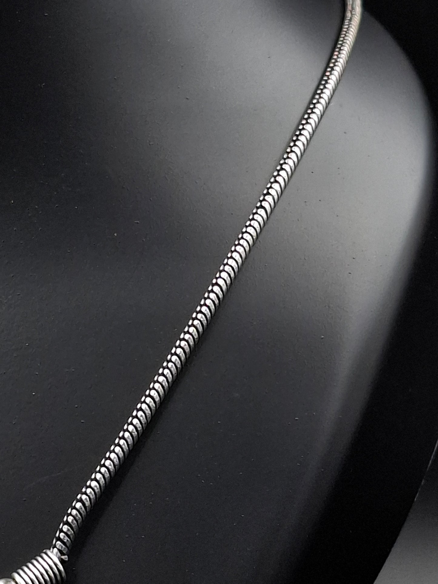 Silver snake chain necklace on a dark background
