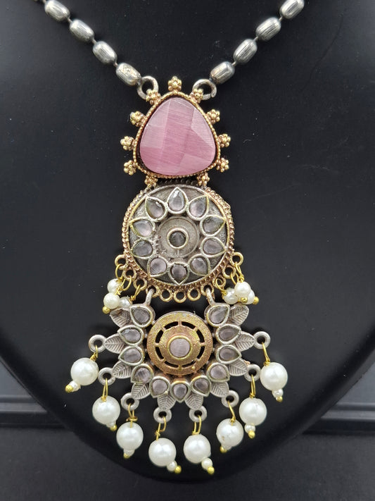 Decorative necklace with pink stone and pearl details on a black background