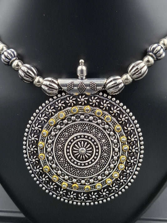Silver and gold decorative pendant on a black background