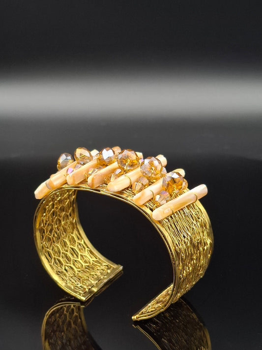 Gold bracelet with intricate design and embedded stones on a black background