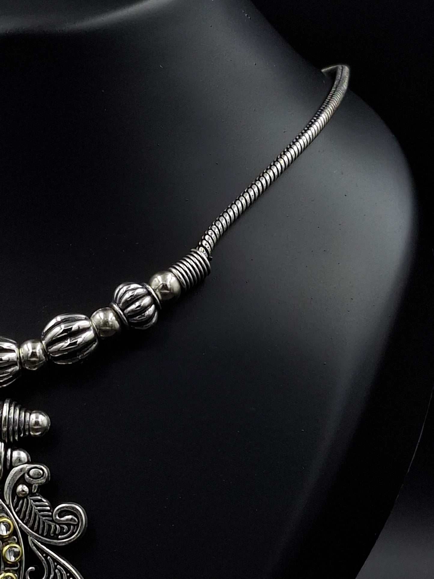 Silver necklace with intricate design on a black background