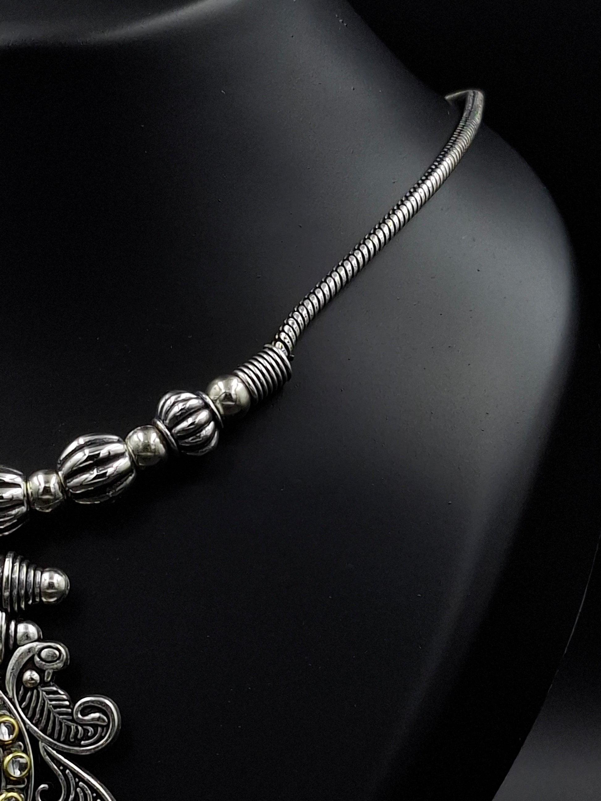 Silver necklace with intricate design on a black background