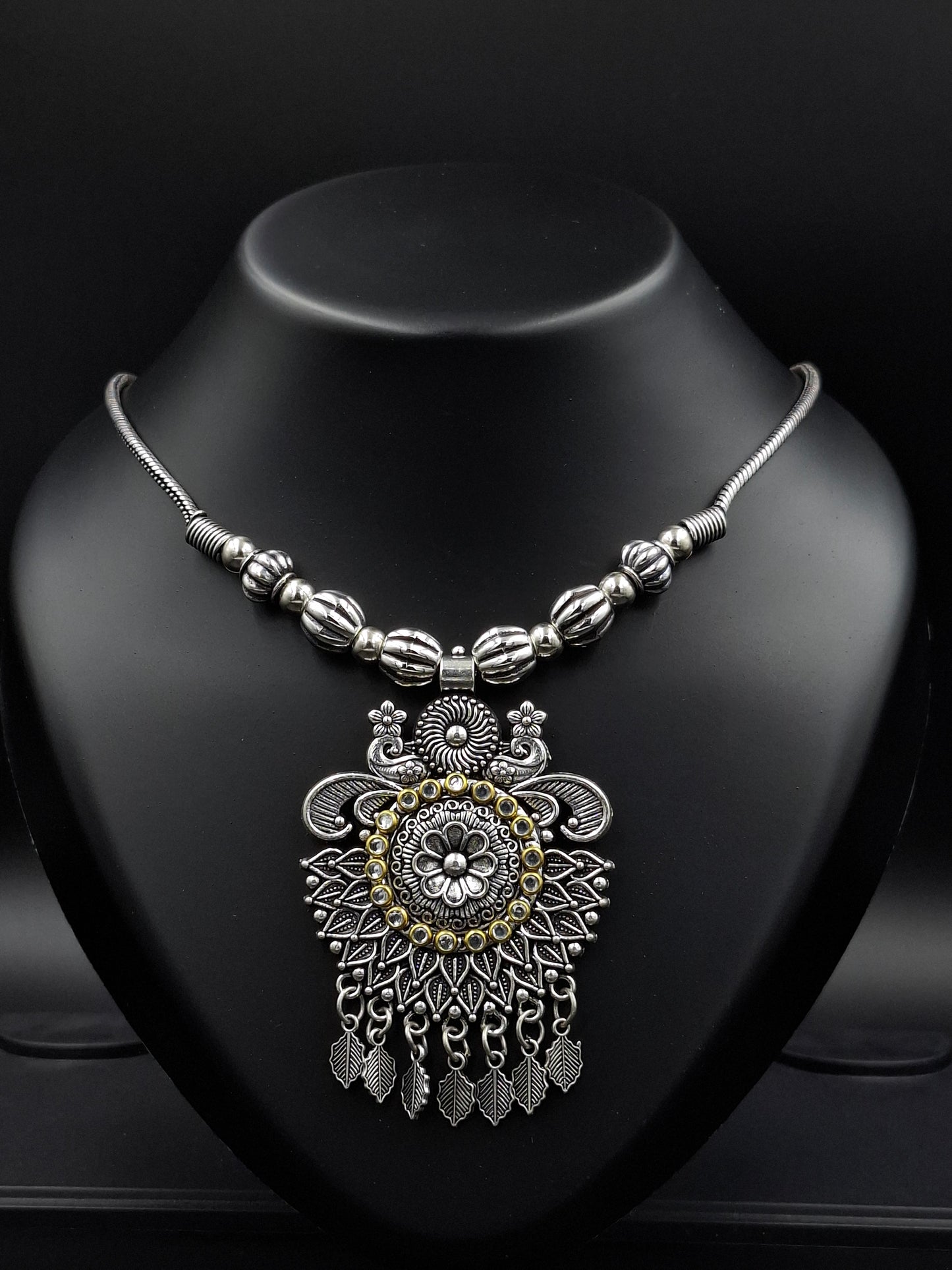 Decorative silver and gold pendant on a dark surface