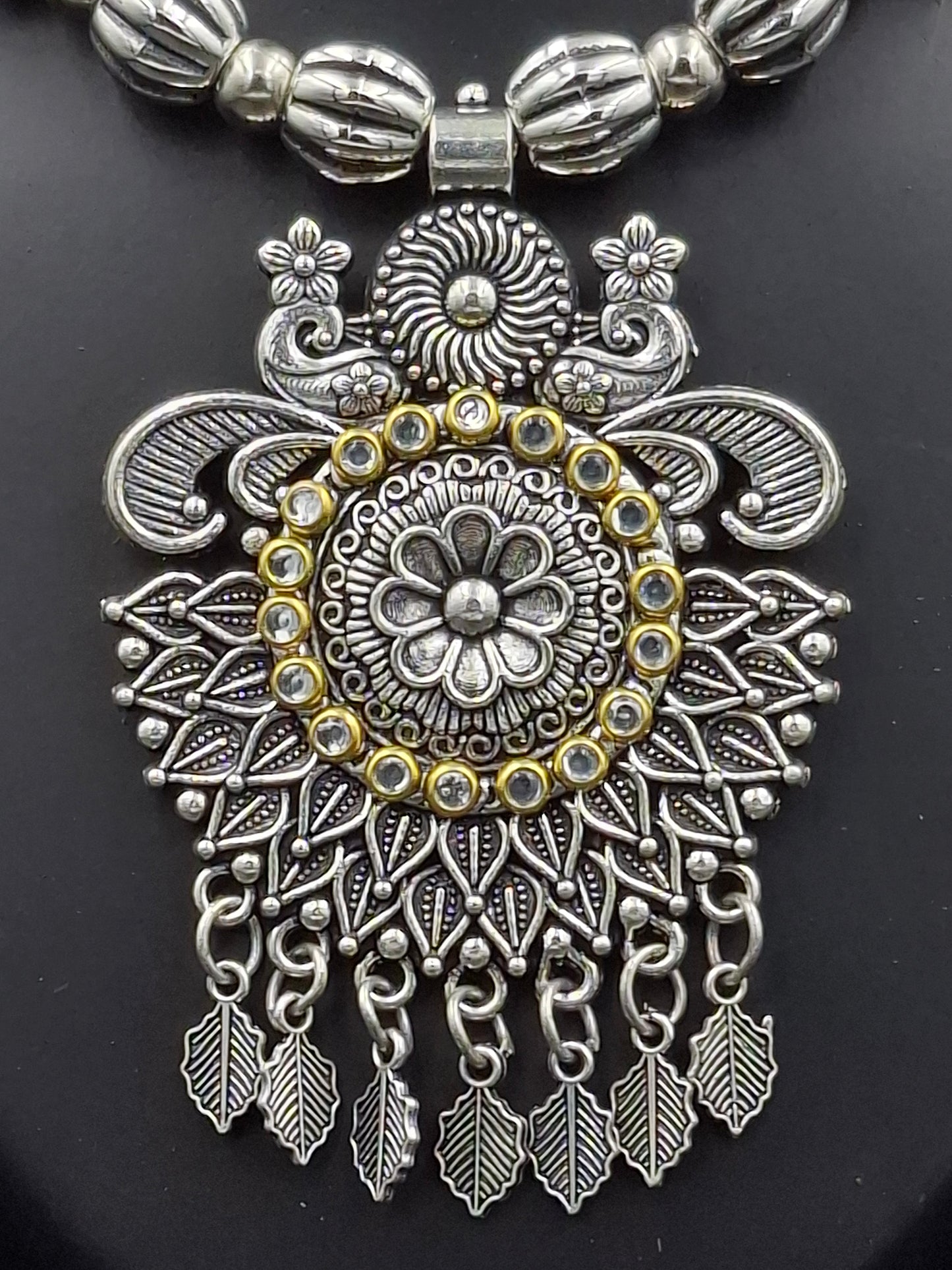 Decorative silver and gold pendant on a black background