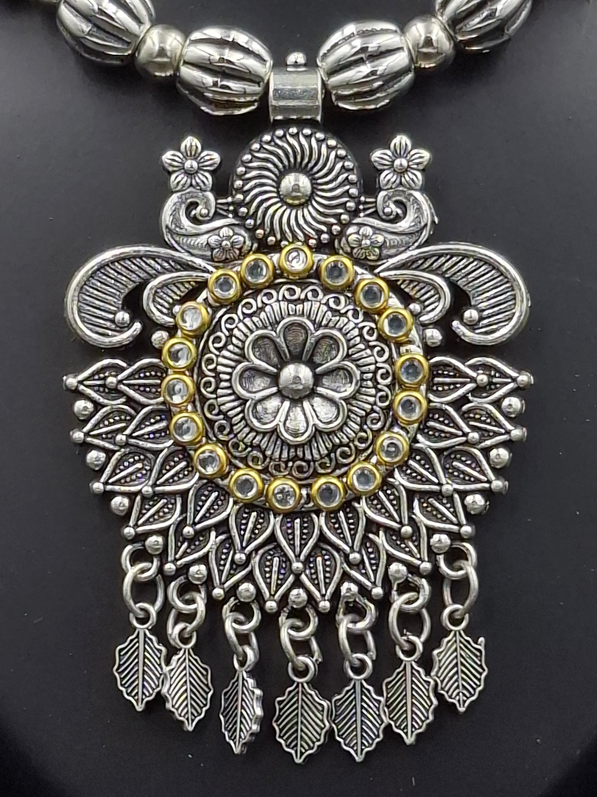 Decorative silver and gold pendant on a black background