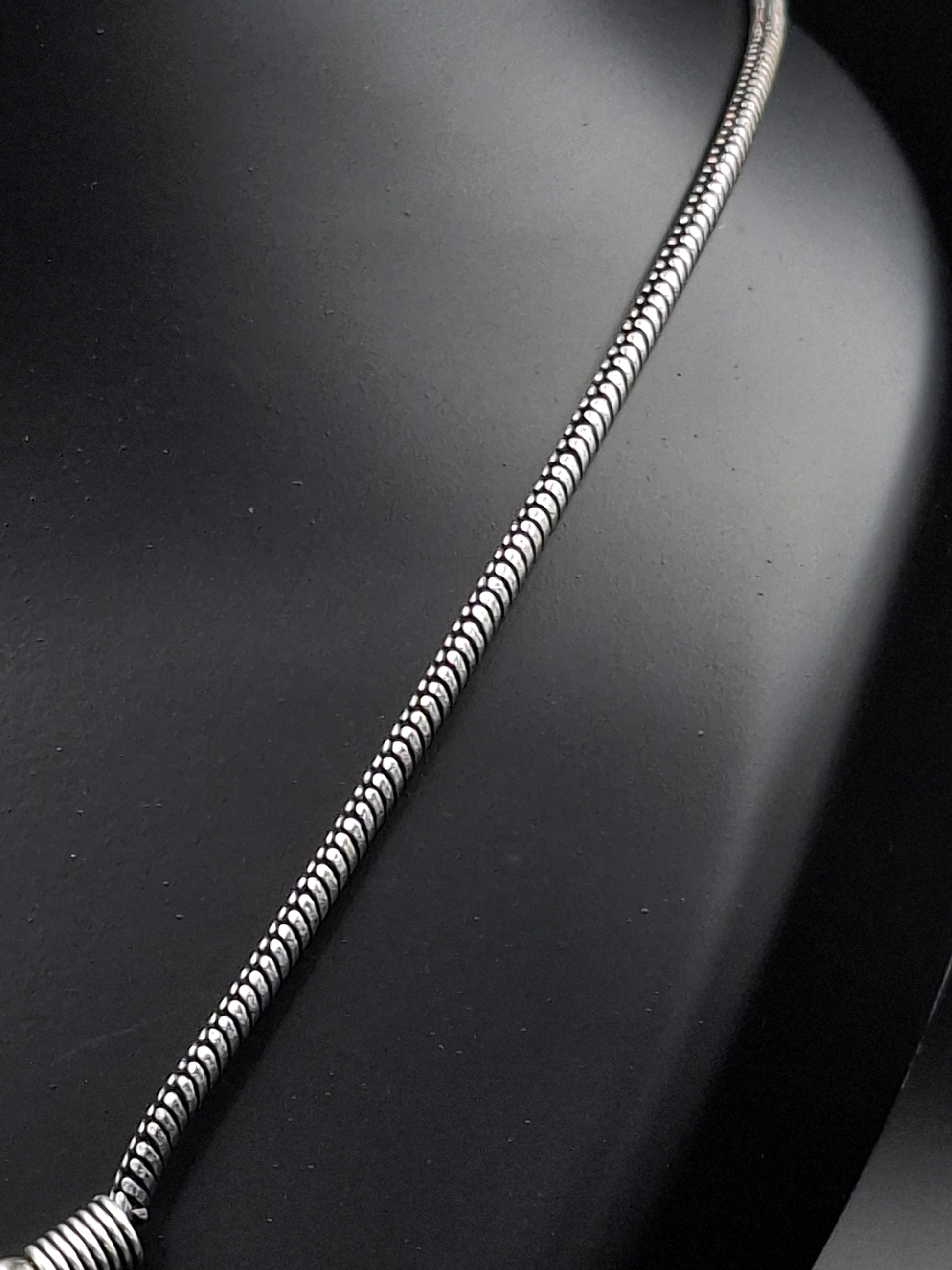Silver snake chain necklace on a dark background