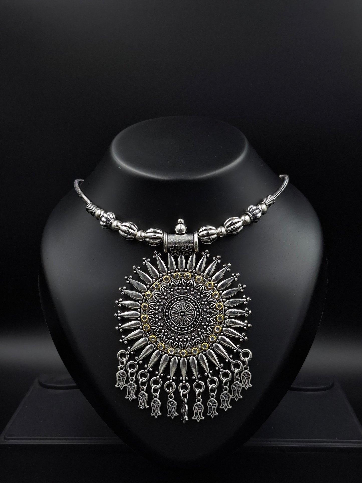 Ornate silver earring on a black stand against a dark background