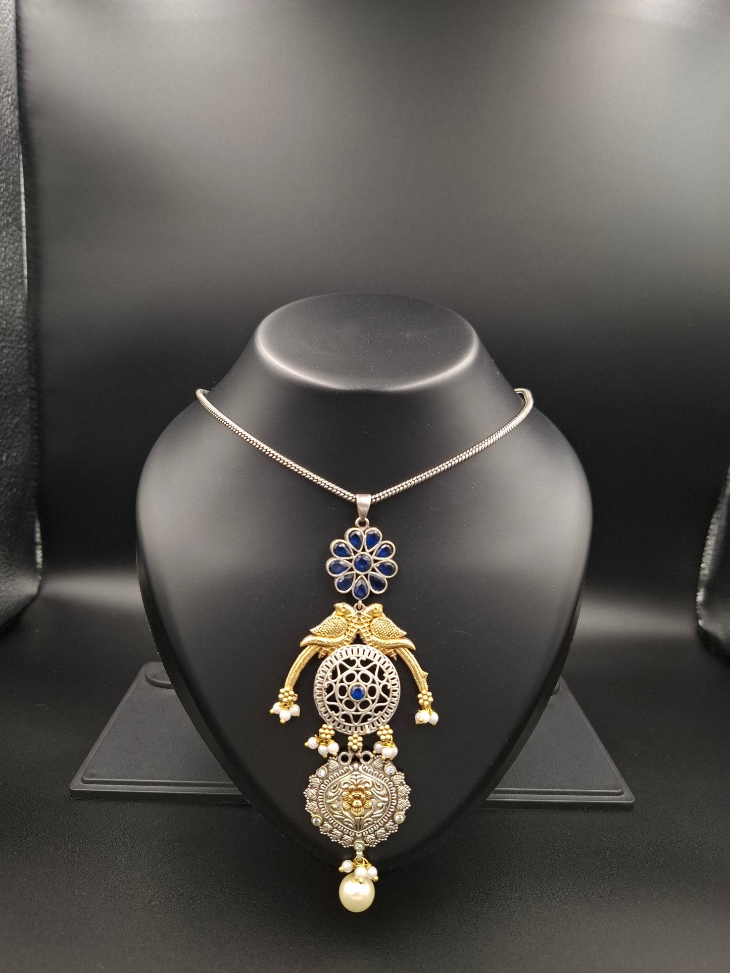 Gold and silver necklace on a black mannequin bust