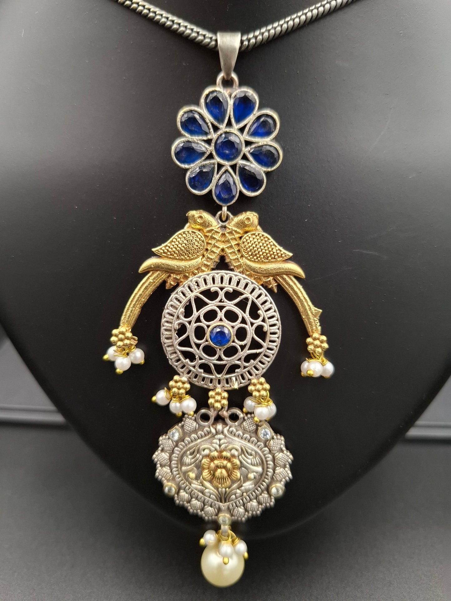Ornate gold and silver necklace with blue stones on a black background