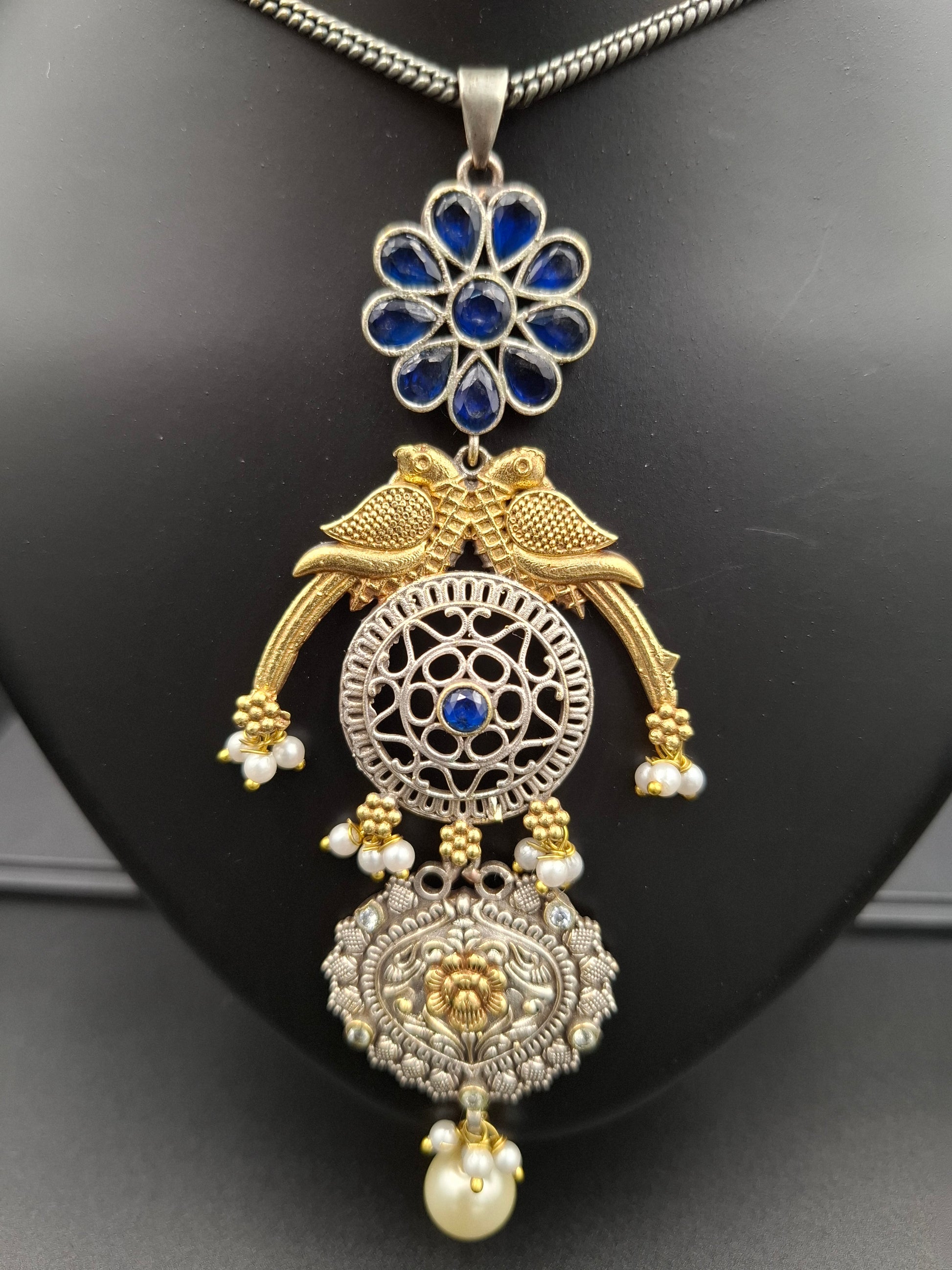Ornate gold and silver necklace with blue stones on a black background