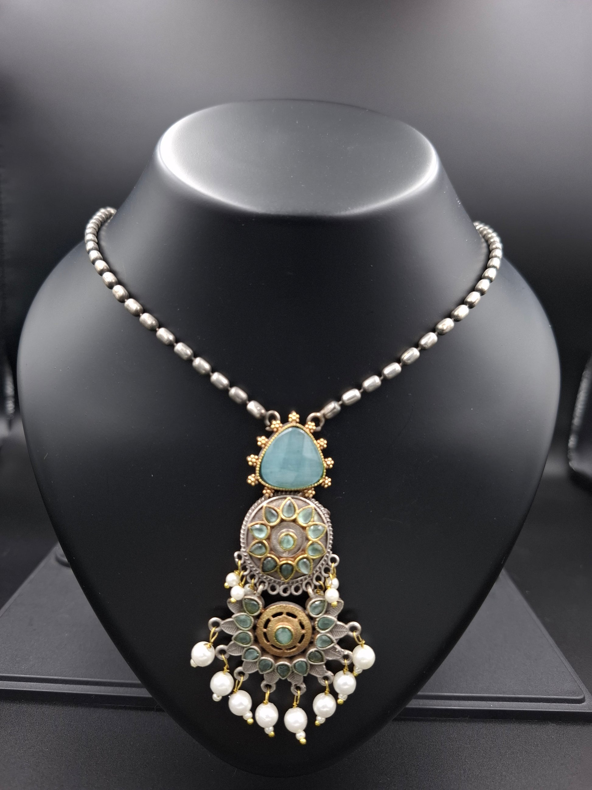 Decorative headband with pearls and gemstones on a black mannequin head.