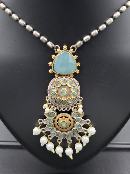 Decorative necklace with turquoise stone and pearl-like elements on a black background