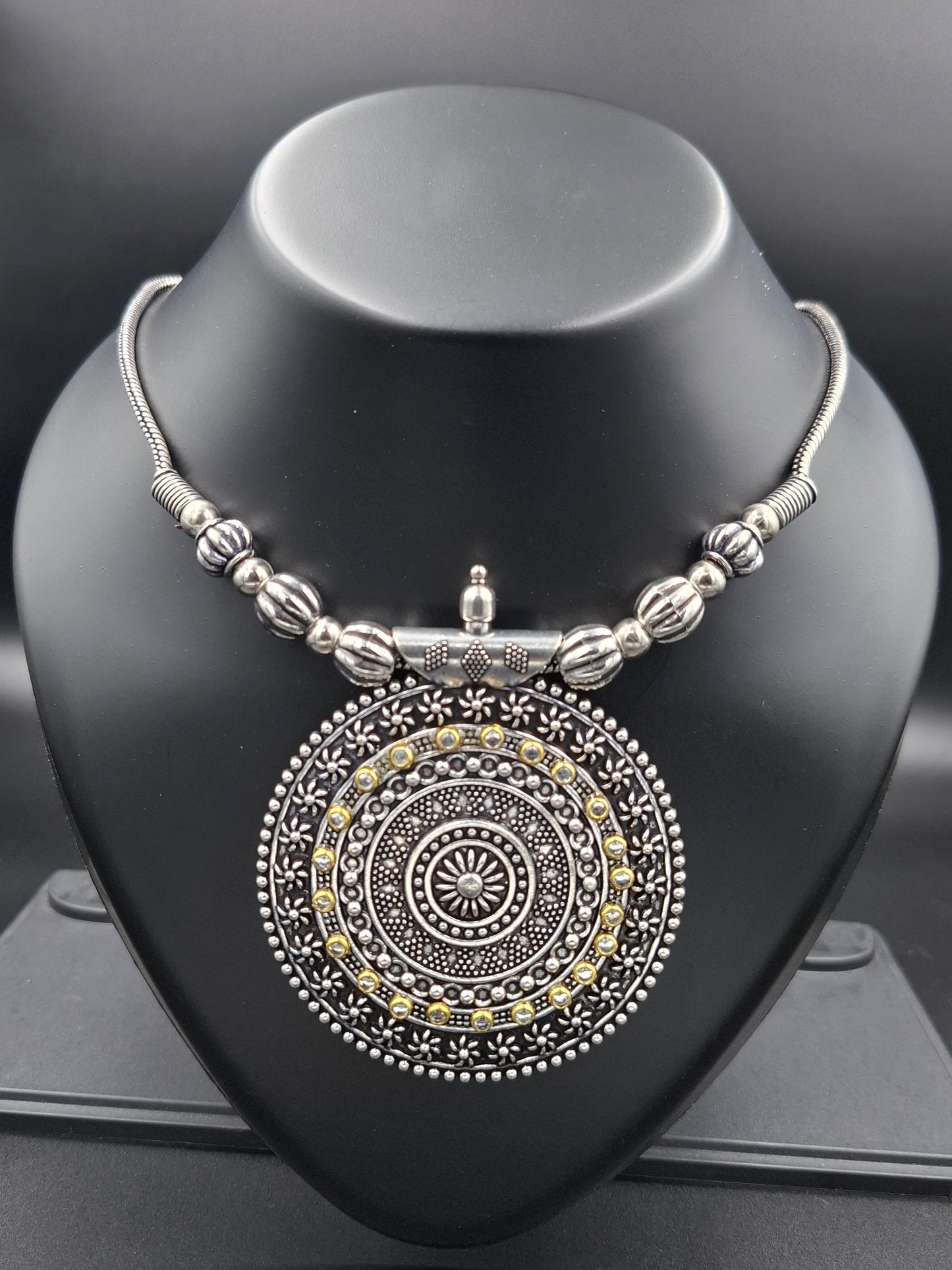 Decorative silver and gold bangle on a black stand