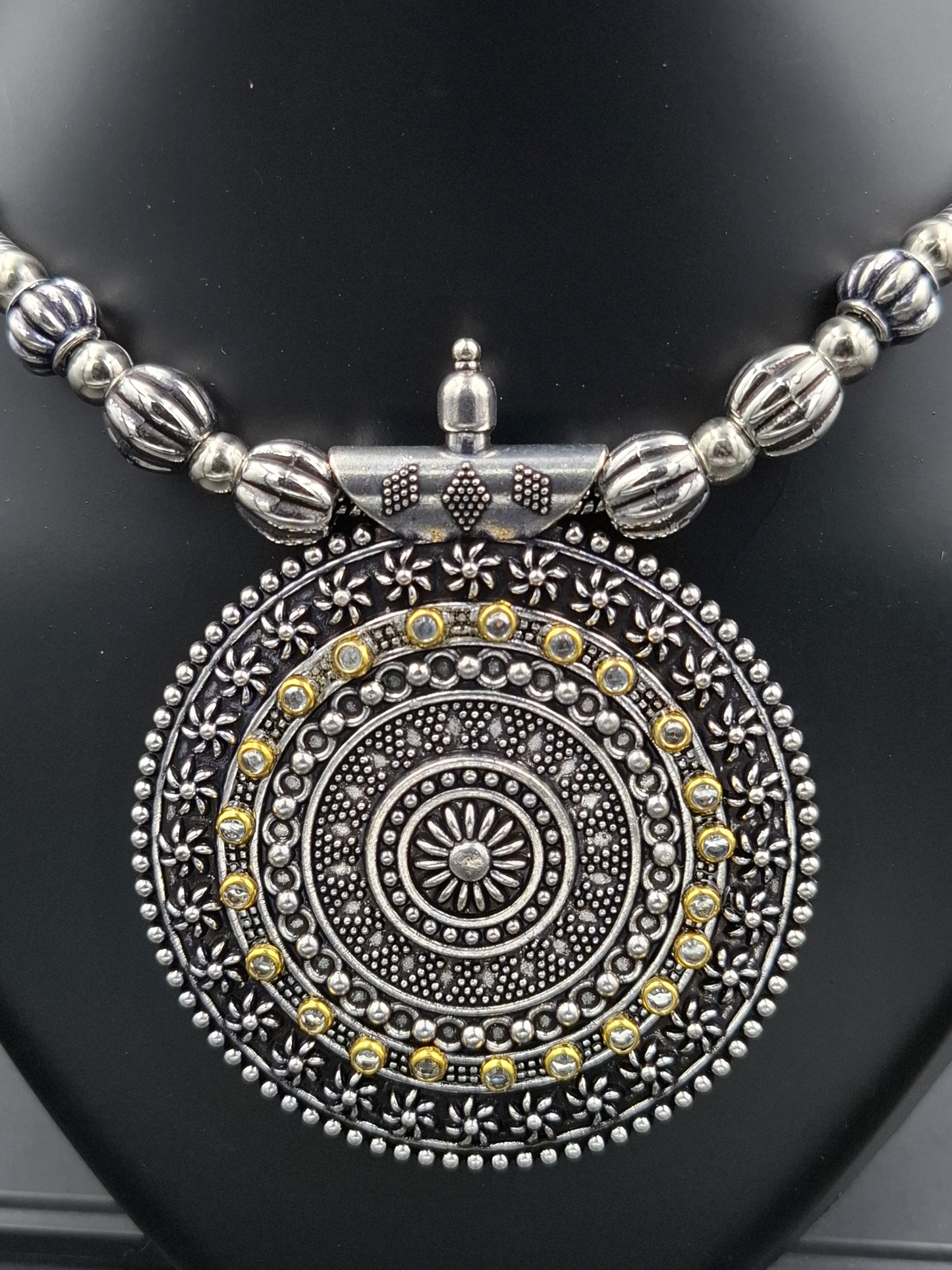 Silver and gold decorative pendant on a black background