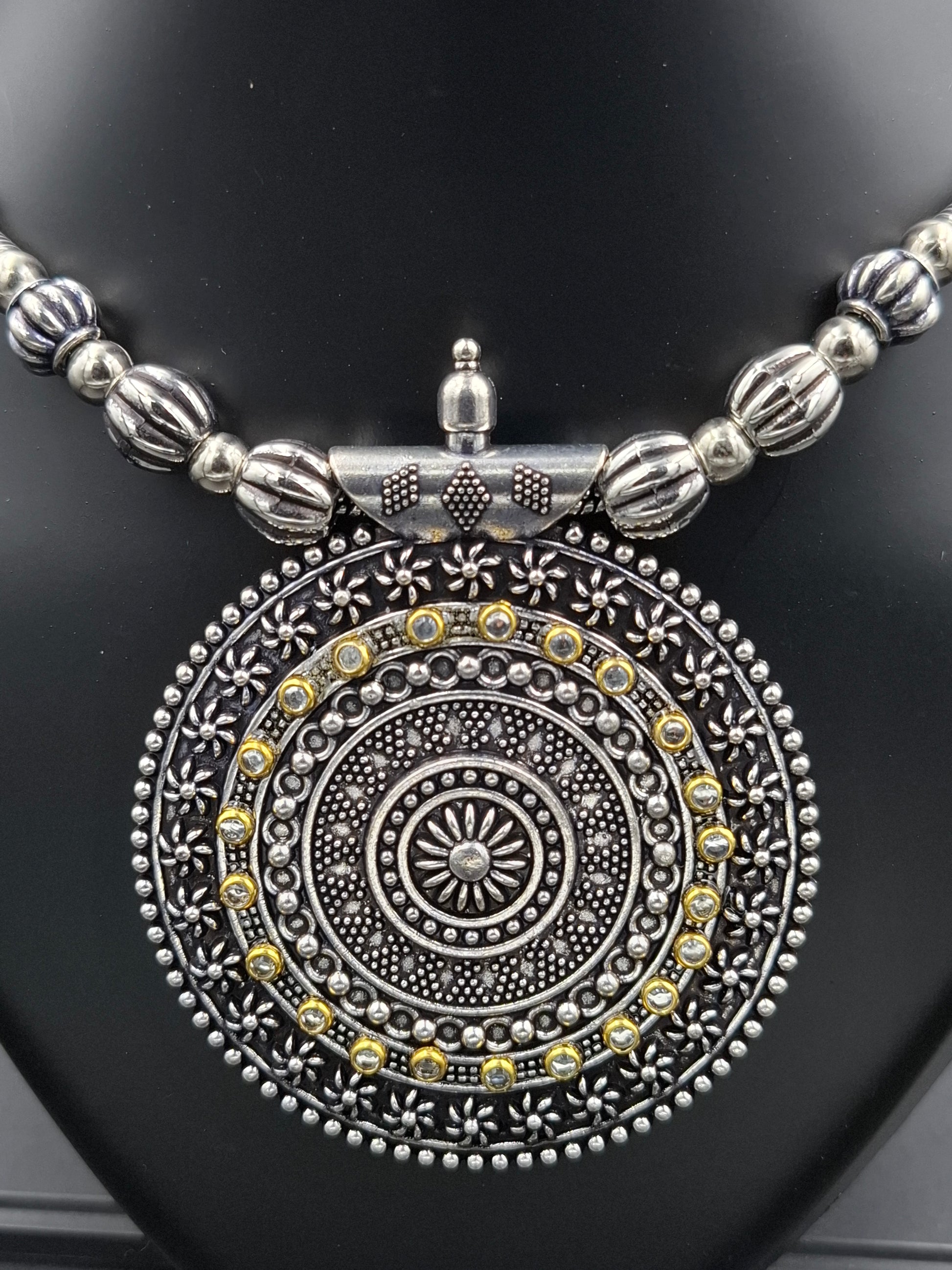 Silver and gold decorative pendant on a black background
