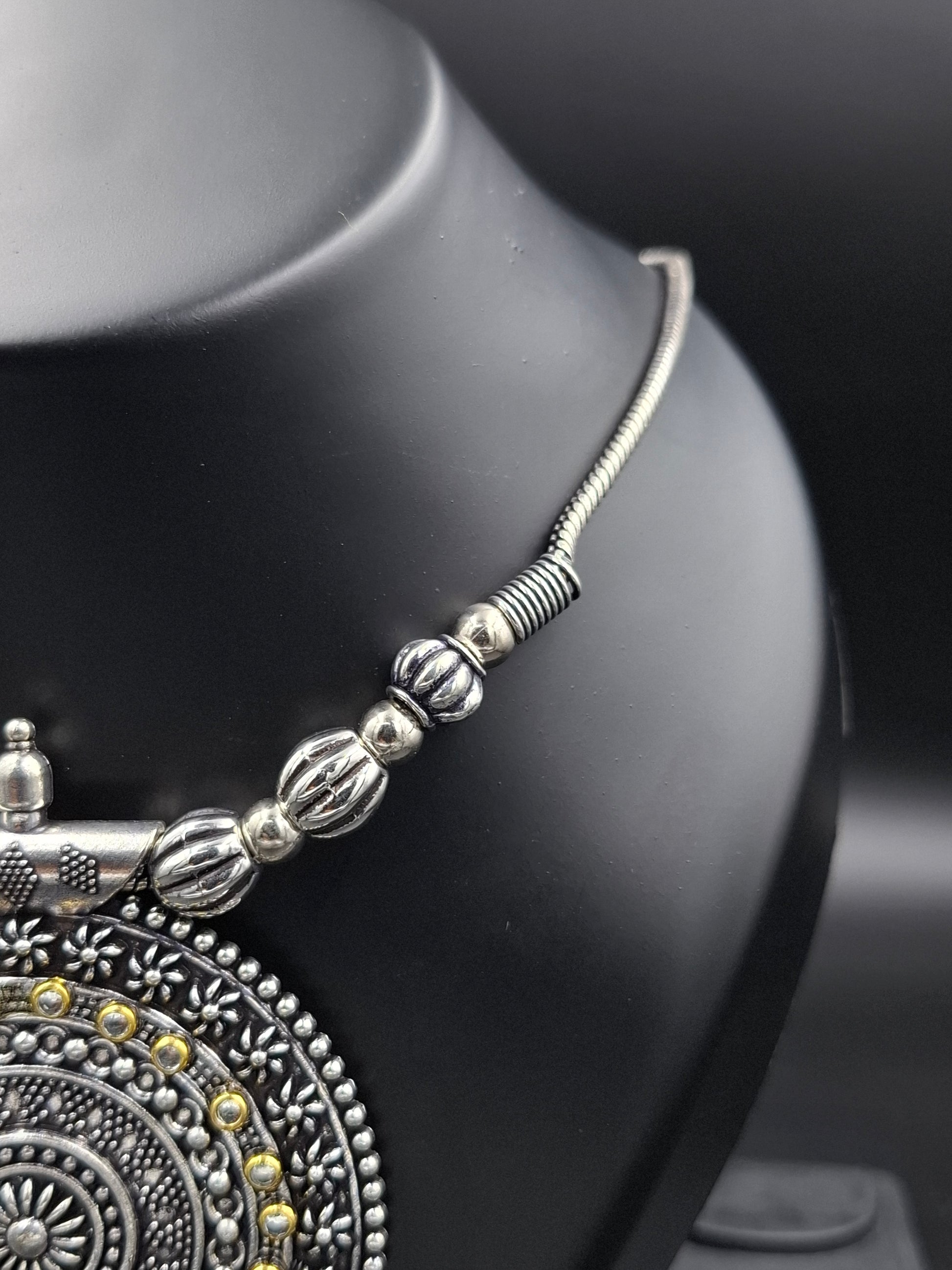 Silver beaded bracelet on a black mannequin with a decorative background