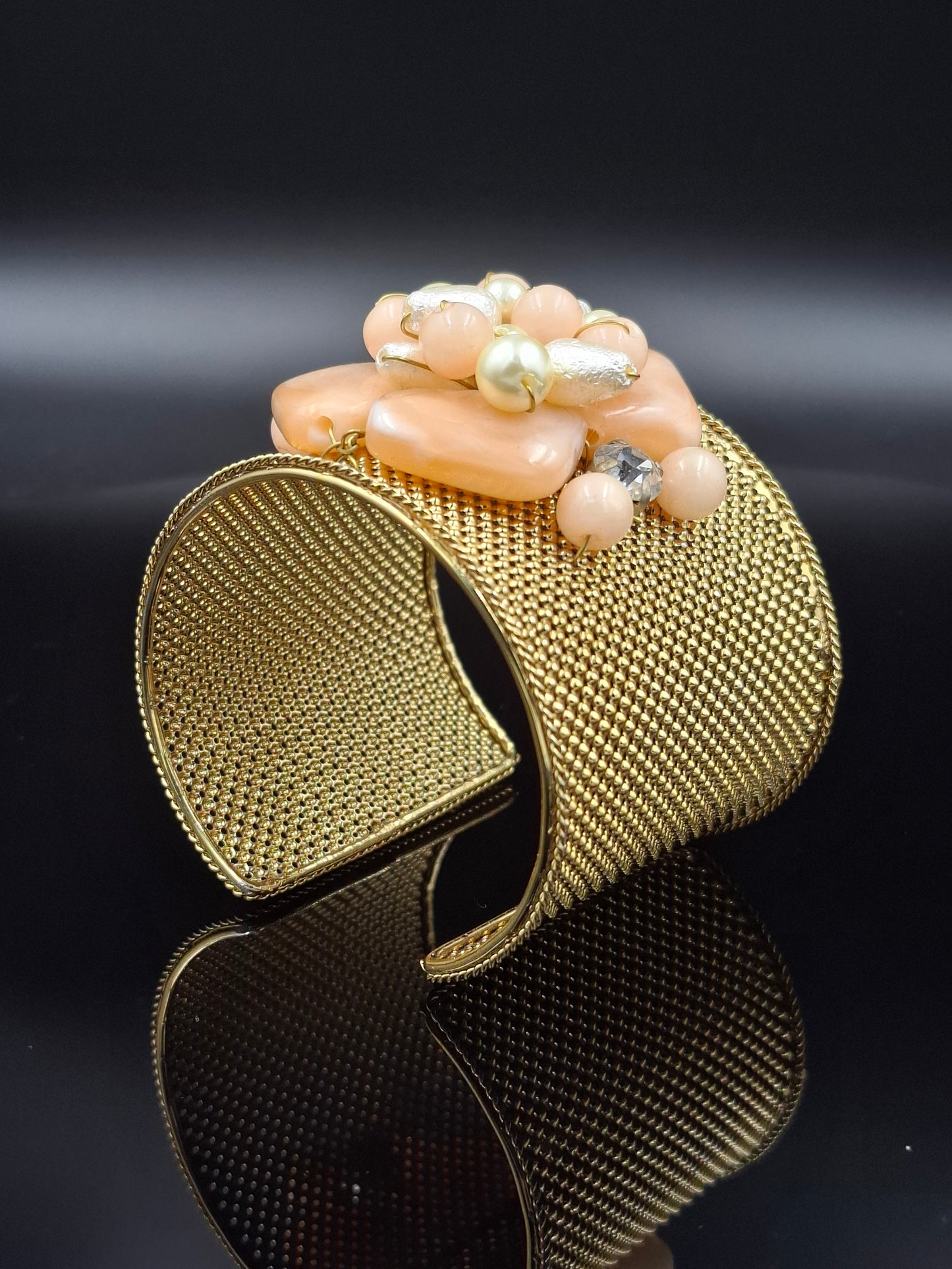 Gold mesh bracelet with a black strap on a dark background