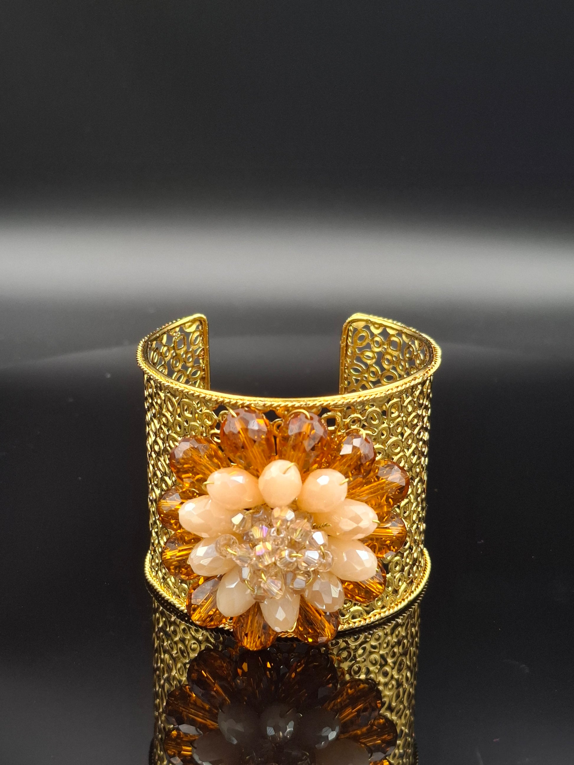 Gold bracelet with floral design on a black background