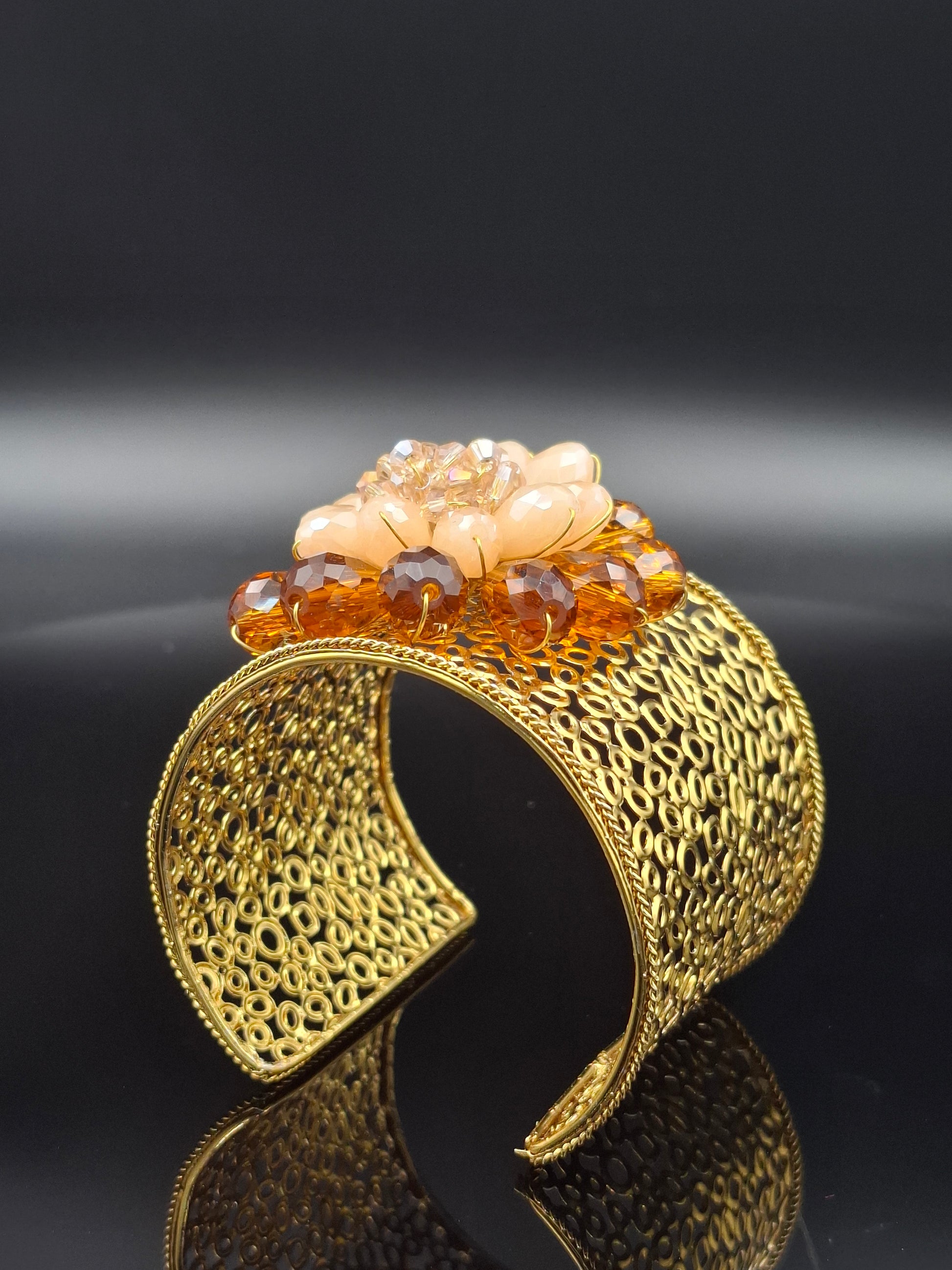 Gold bracelet with intricate design on a black background