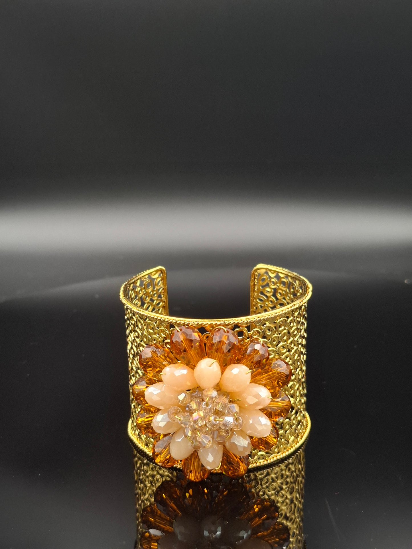 Gold bracelet with floral design on a black background