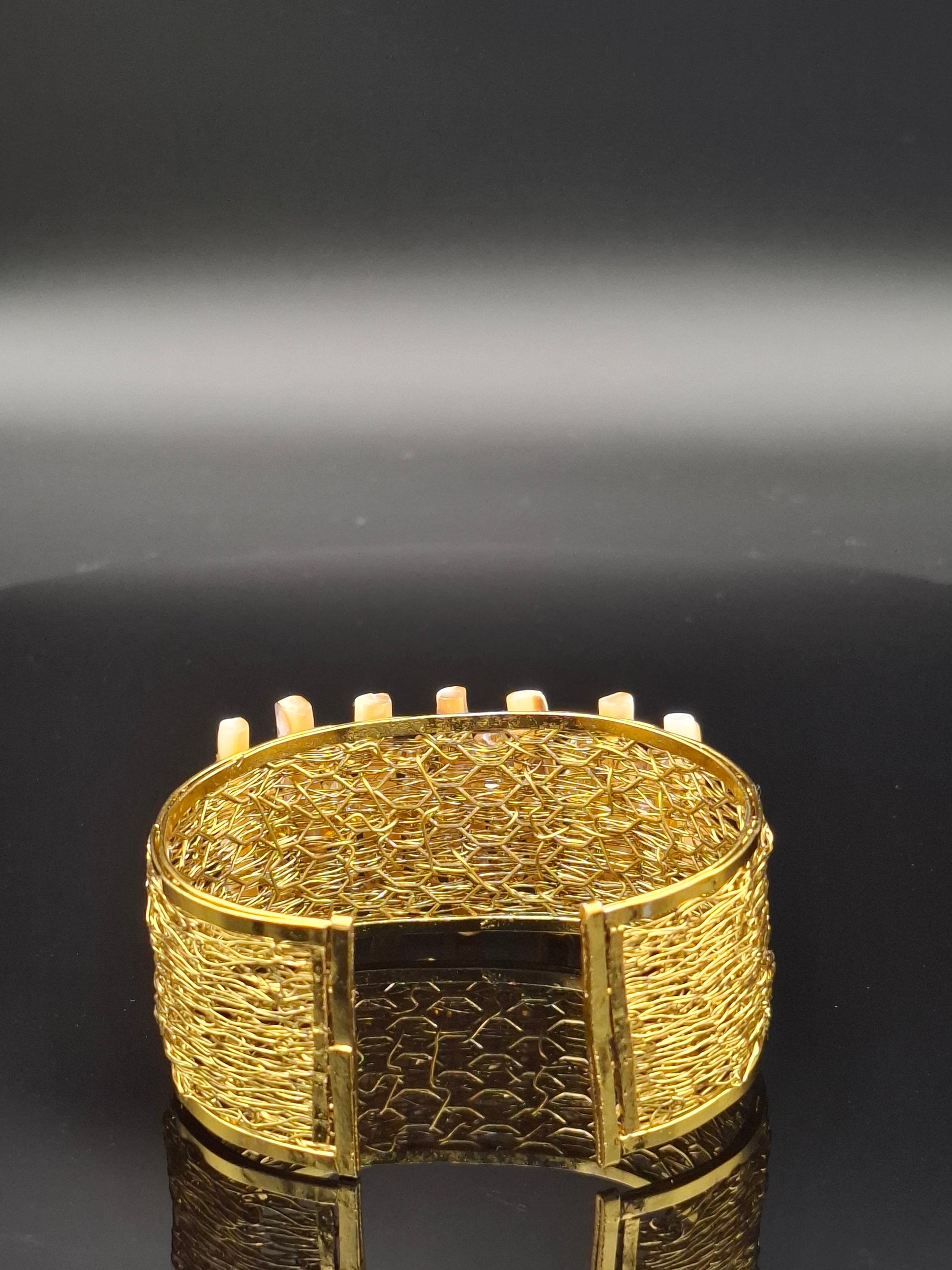 Close-up of a gold bracelet with intricate design on a black background